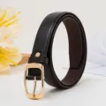 Gros plan détaillé d'une ceinture en cuir pour femme avec une boucle ardillon dorée. - Café