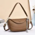 Detailed view of the elegant brown leather crossbody bag with chic tassel pendant and hardware. - Brown