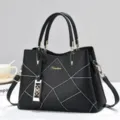 Dettaglio borsa a mano donna nera con cuciture geometriche, elegante e raffinato design dorato. - Nero