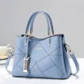 Vista dettagliata della borsa in pelle azzurra con cuciture geometriche e dettagli dorati. - Celeste