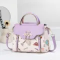 Detailed view of the stylish purple and white leather handbag showcasing exquisite metal swan clasp. - Purple