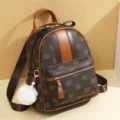 Women brown monogram mini backpack with furry pom pom charm and front zip pocket variant. - Large BE Style / Brown