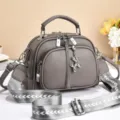 Stylish grey leather crossbody shoulder bag with wide strap and cute balloon dog charm. - Cartoon Zipper / Gray