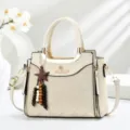 Chic beige handbag detail view featuring elegant metal handle, charm, and branded embossed design. - Off White