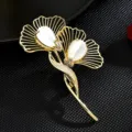 Elegante broche de hoja de ginkgo dorada con cabujón blanco y detalles de cristales. - Blanco