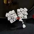 Elegante waaierachtige broche met sprankelende zirkonia, rode middensteen en hangende druppel. - Waaier Vormige Hanger Broche