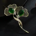 Elegante broche de hoja de ginkgo con piedra verde y cristales brillantes, accesorio dorado. - Verde