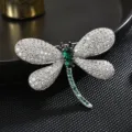Exquisita broche de libélula plateada con circonitas brillantes y llamativos cristales verdes. - Plateado