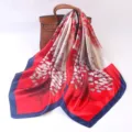 Detail shot of a vibrant red silk square scarf with artistic tree print and blue border. - Small Red Leaves