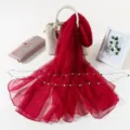Detailed view of a vibrant red chiffon silk scarf styled with decorative props on white. - Burgundy