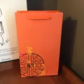 Orange paper gift bag with oriental design, perfect for silk scarves and holiday gifts. - Antique Style Plum Blossom Tote Box
