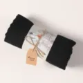 Detailed view of rolled black cotton linen scarf with elegant printed paper packaging band. - Black