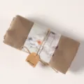 Detailed close-up shot of a rolled khaki cotton linen scarf wrapped with lotus art paper and tag. - Khaki