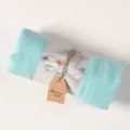Close-up detail of rolled light blue cotton linen scarf shawl with lotus paper wrap tag. - Fresh Blue