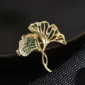 Elegante broche de doble hoja de ginkgo con circonitas verdes imagen principal mujer. - Verde