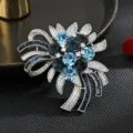Elegante broche de flor de cristal con pedrería azul brillante y base de metal plateado. - Azul