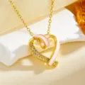 Detail shot of a gold heart pendant necklace with pink enamel and sparkling clear zirconia stones. - Pink Hollow Heart Necklace / Gold