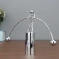 Detailopname van het zilverkleurige metalen balancerende mannetje als bureau ornament. - Grote tweebenige balancerende ijzeren man