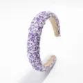 Detalle en primer plano de una diadema acolchada ancha con lentejuelas moradas y blancas. - Violeta