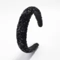 Primer plano detallado de la diadema acolchada negra brillante con diamantes de imitación. - Negro