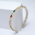 Gros plan d'un serre-tête baroque en strass avec cristaux colorés et bordure dorée. - Arc-en-ciel