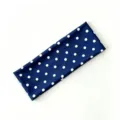 Vista dettagliata di una fascia elastica blu a pois bianchi, morbido accessorio per capelli. - Pois Blu Notte