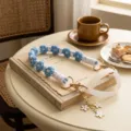 Detailed view of the handmade blue and white woven cup strap with metal clasp and silicone ring. - White Ring + Blue Daisy Lanyard & Floral Pendant