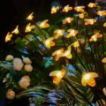 Detailansicht von solarbetriebenen Bienen-LED-Lichterketten im Gartengras leuchtend. - 6-LED Solarleuchte mit Warmlicht