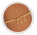 Gold bead bracelet detail featuring a charming bow and initial letter C pendant design. - Letter C