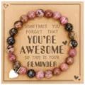 Detailed view of a handmade beaded gemstone bracelet with a stainless steel heart charm card. - Black Line Red Jasper + AWESOME Card
