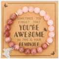 Detailed view of the handmade gemstone beaded bracelet with a shiny rhinestone butterfly charm. - Rose Quartz & Rhodochrosite with AWESOME Card