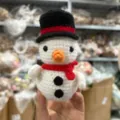 Detailed close-up of a handmade crochet snowman ornament with cute red scarf and hat. - Snowman