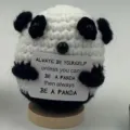 Detailed shot of handmade crochet panda doll with inspirational quote card on wooden base. - Panda