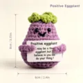 Nahaufnahme eines süßen handgemachten Häkel-Auberginen-Plüschtiers mit inspirierender Karte. - Aubergine