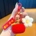 Gestrickter Frucht-Schlüsselanhänger mit weißer Blume und rotem Segen-Etikett für Deko. - Frieden- und Freude-Kaki mit buntem Haken