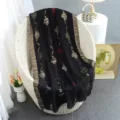 Elegant black shawl featuring metallic gold floral cut-work and detailed border design in cozy indoor setting. - Black Monogram