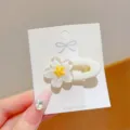 Close-up detail view of the clear floral hair clip with yellow center on white card. - White Oval Flower Clip