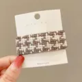 Close-up detail of a brown and white tweed hair clip on a white card, elegant winter hair accessory. - Square / Brown Plaid
