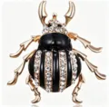 Close-up detail of rhinestone beetle brooch showing shiny crystal and gold alloy craftsmanship. - White
