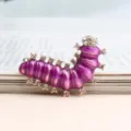 Closeup detail of the purple enamel rhinestone caterpillar brooch with shiny crystal stones. - Purple