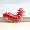 Detailopname van een charmante rode emaille rups broche versierd met sprankelende strass steentjes. - Rood