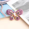 Detailed view of 3D hollow butterfly brooch with purple rhinestones and iridescent center stone. - Purple
