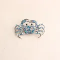 Detailed view of a sparkling rhinestone crab brooch, alloy material with blue crystals. - Blue