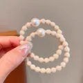 Detailopname van het stijlvolle beige parelhaarelastiek met een zachte en elastische band. - Beige