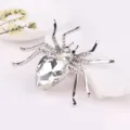 Exquisite silver-tone spider brooch featuring dazzling rhinestones and a large crystal teardrop. - Silver + White