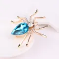 Prachtige strass spin broche met een blauw kristallen lichaam en fonkelende steentjes. - Goud + Meerblauw
