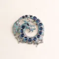 Vista detallada de un broche vintage de dragón con diamantes de imitación y cristales azules. - Azul