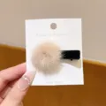 Close-up detail of the cute fluffy faux fur ball hair clip on a display card, soft plush texture. - Bobby Pin / Khaki
