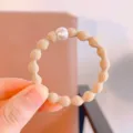 Simple basic bean hair tie detail view, elastic rubber band with single white pearl decor. - Pearl Beige