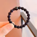 Detail view of the black wavy elastic hair tie with small bead, simple daily hair accessory. - Solid Black
